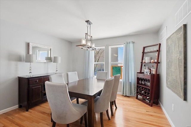 dining room with light wood finished floors, baseboards, visible vents, and a chandelier