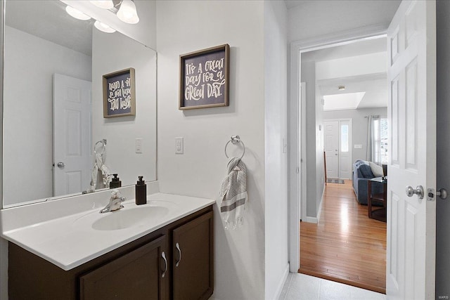 bathroom featuring a skylight, wood finished floors, vanity, and baseboards