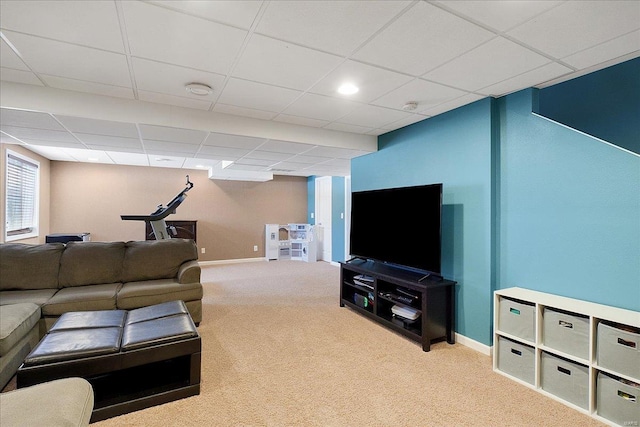 carpeted living area with a drop ceiling and baseboards