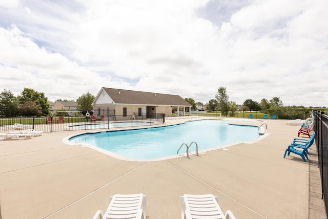 community pool with a patio area and fence