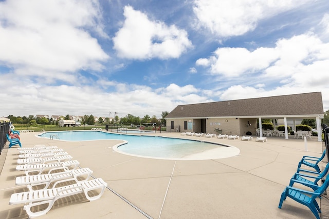 community pool with a patio area and fence