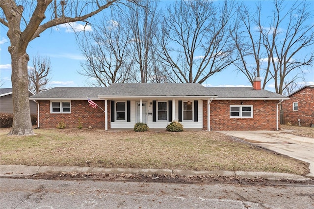 ranch-style home with a chimney, a front lawn, concrete driveway, and brick siding