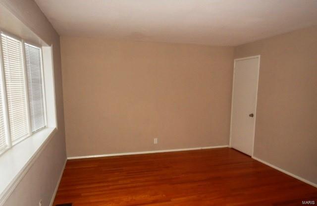 unfurnished room with plenty of natural light, wood finished floors, and baseboards