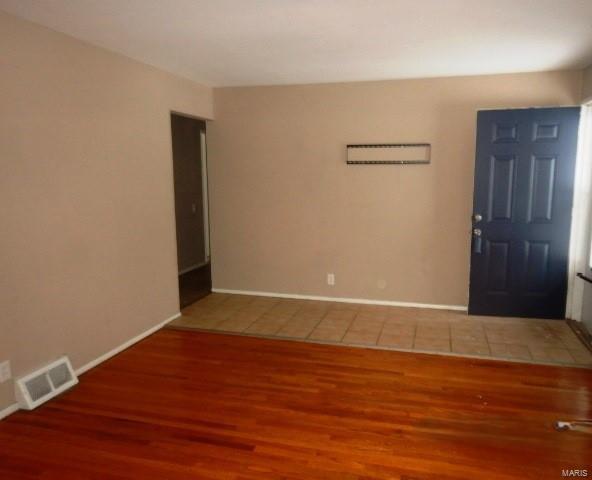 foyer entrance with visible vents, baseboards, and wood finished floors