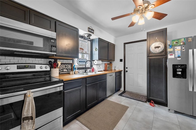 kitchen featuring light tile patterned floors, decorative backsplash, butcher block countertops, stainless steel appliances, and a sink