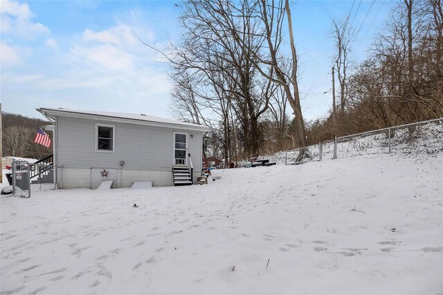 snow covered back of property with a garage and fence