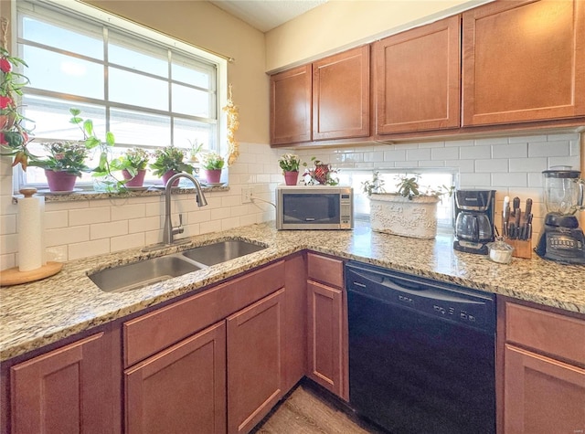 kitchen with tasteful backsplash, stainless steel microwave, a sink, light stone countertops, and dishwasher