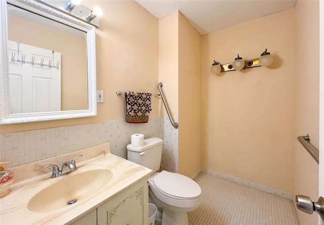 bathroom featuring a textured ceiling, toilet, a wainscoted wall, vanity, and tile patterned floors