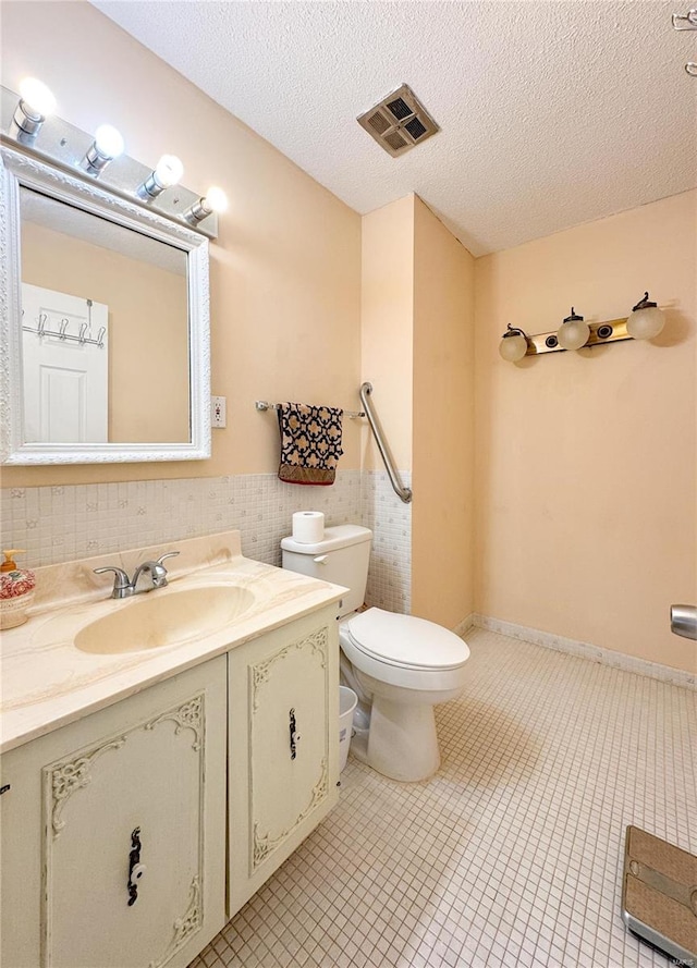 bathroom with a wainscoted wall, visible vents, toilet, a textured ceiling, and vanity