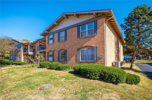 view of front of property with a front lawn, central AC, and brick siding