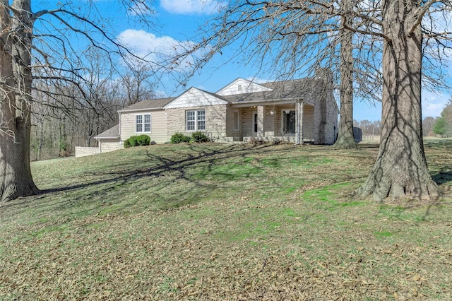 view of front of property featuring covered porch, stone siding, and a front yard