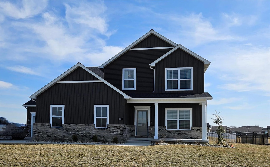 craftsman inspired home featuring brick siding, board and batten siding, a front yard, and fence