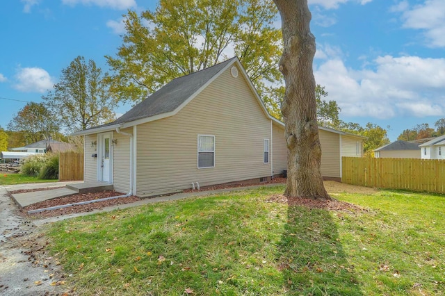 view of side of home featuring fence and a yard