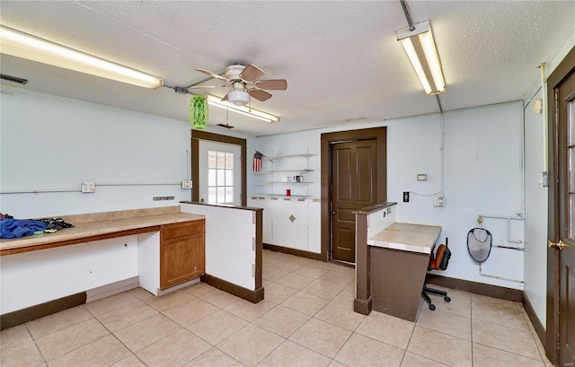 kitchen featuring a textured ceiling, light countertops, light tile patterned floors, and brown cabinets