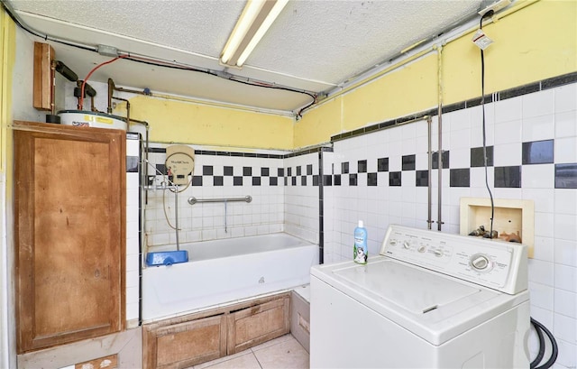 laundry room featuring washer / dryer, laundry area, light tile patterned floors, a textured ceiling, and tile walls