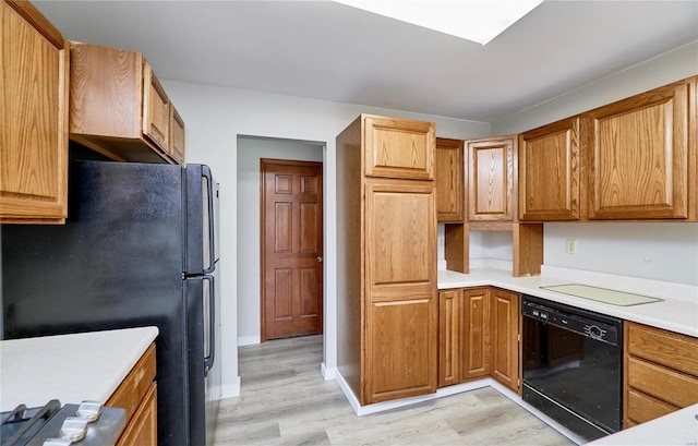 kitchen featuring black dishwasher, light countertops, light wood finished floors, and freestanding refrigerator