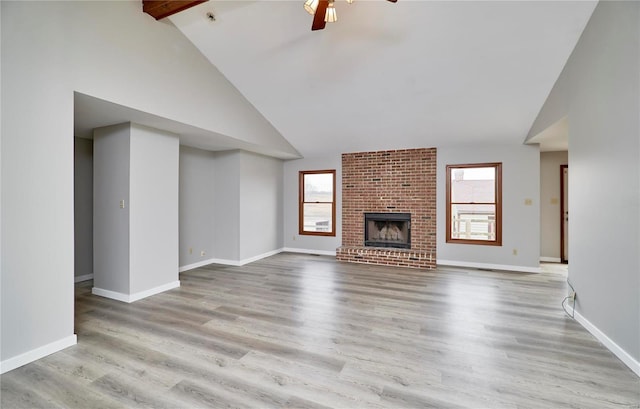 unfurnished living room with light wood-style floors, plenty of natural light, a fireplace, and high vaulted ceiling