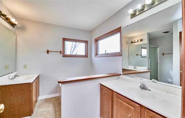 bathroom with tile patterned flooring, two vanities, a sink, and toilet