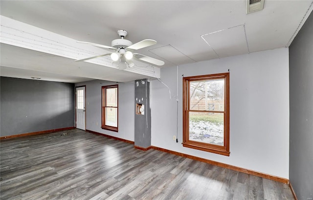 spare room with a ceiling fan, wood finished floors, visible vents, and baseboards