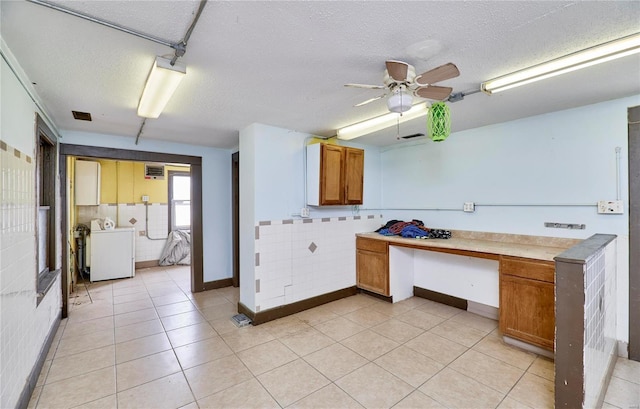 kitchen featuring a textured ceiling, light countertops, brown cabinetry, and washer / dryer