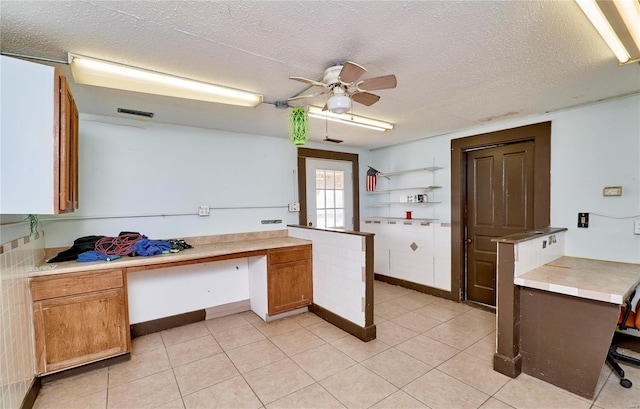 kitchen featuring light countertops, built in desk, and brown cabinetry