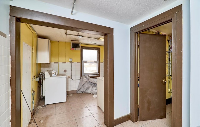 laundry room featuring a textured ceiling, washer / clothes dryer, light tile patterned floors, and cabinet space