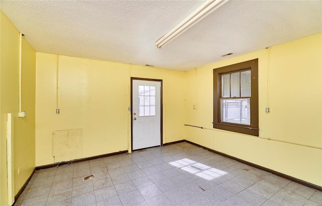 empty room featuring a textured ceiling and baseboards