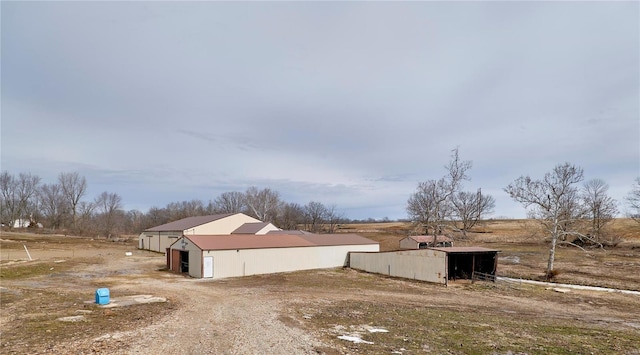 view of property exterior featuring a pole building, a rural view, and an outdoor structure