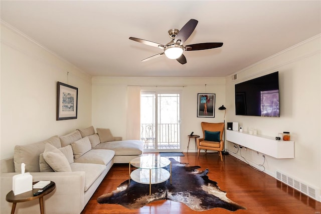 living area with a ceiling fan, wood finished floors, visible vents, and crown molding