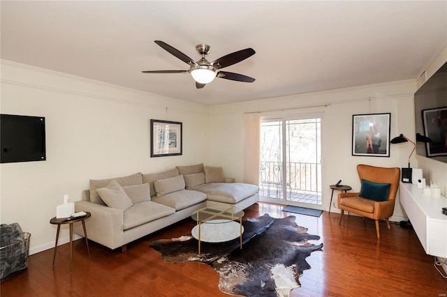 living room featuring ceiling fan, crown molding, baseboards, and wood finished floors