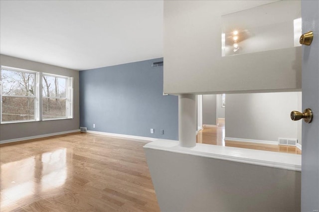 unfurnished living room with visible vents, baseboards, and wood finished floors