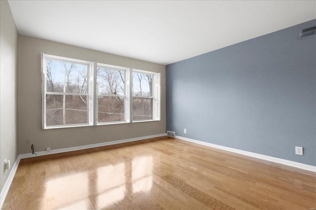 empty room featuring visible vents, baseboards, and wood finished floors