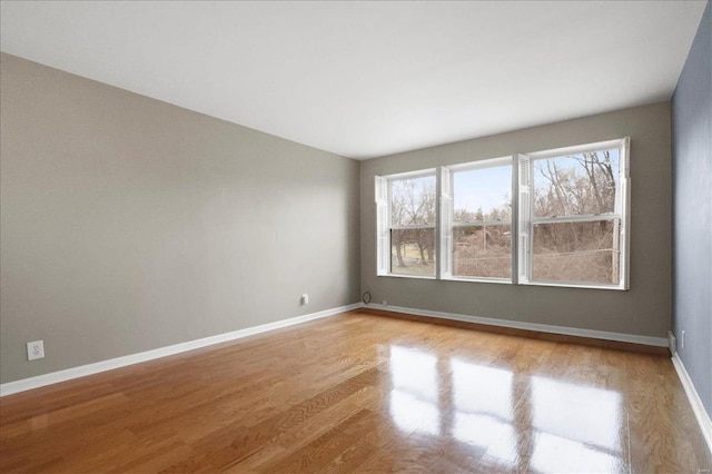 spare room with baseboards and wood finished floors