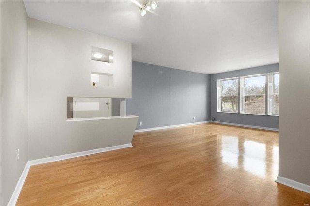 unfurnished living room featuring baseboards and wood finished floors