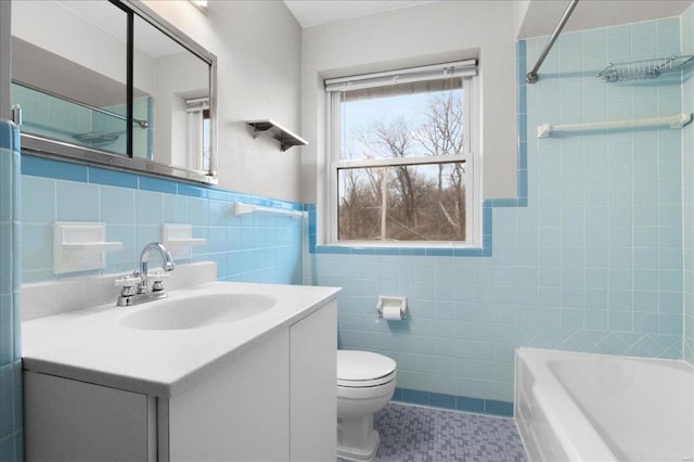 full bath with a wainscoted wall, toilet, vanity, tile patterned floors, and tile walls