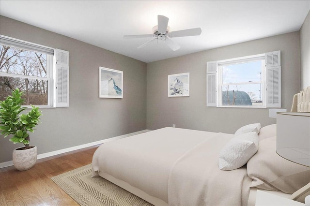 bedroom with baseboards, wood finished floors, and a ceiling fan