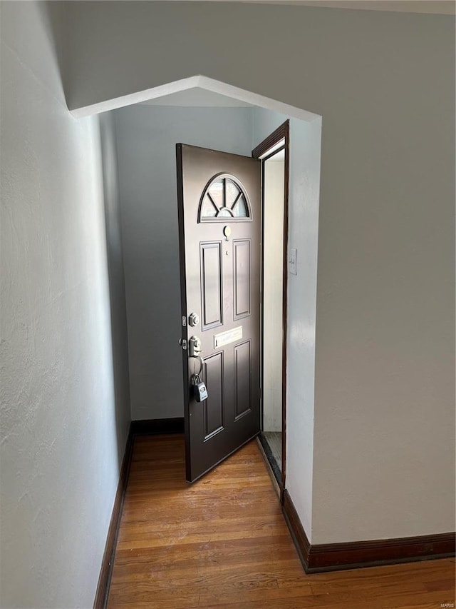 doorway to outside featuring baseboards and wood finished floors