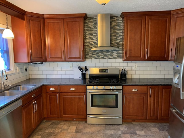 kitchen featuring a sink, dark stone countertops, stainless steel appliances, wall chimney range hood, and decorative backsplash