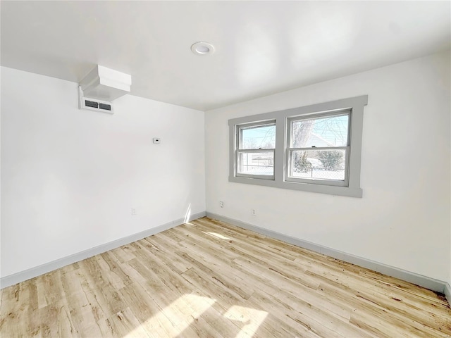 empty room featuring light wood-style floors, baseboards, and visible vents