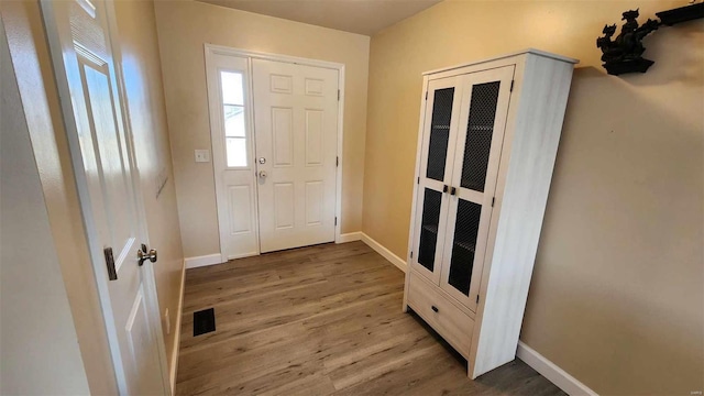 foyer entrance with wood finished floors, visible vents, and baseboards