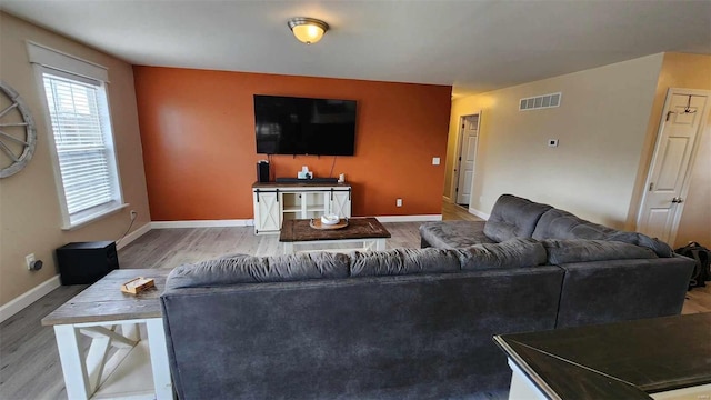 living room with baseboards, visible vents, and wood finished floors