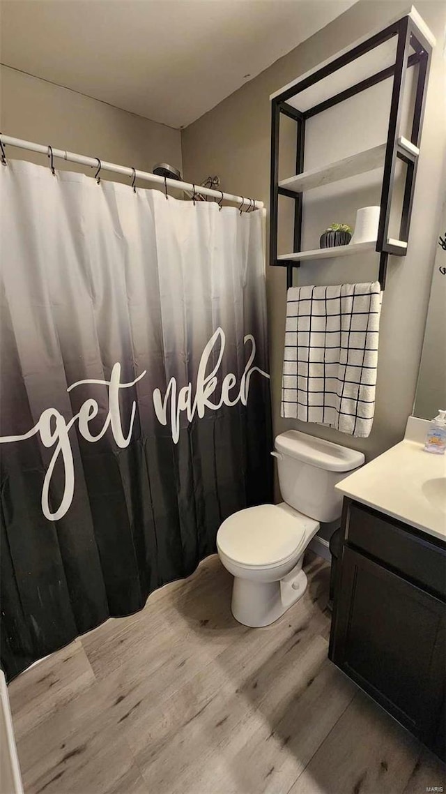 full bath with toilet, a shower with curtain, wood finished floors, and vanity