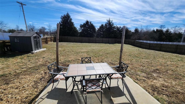 view of patio with outdoor dining space, a fenced backyard, an outdoor structure, and a storage unit