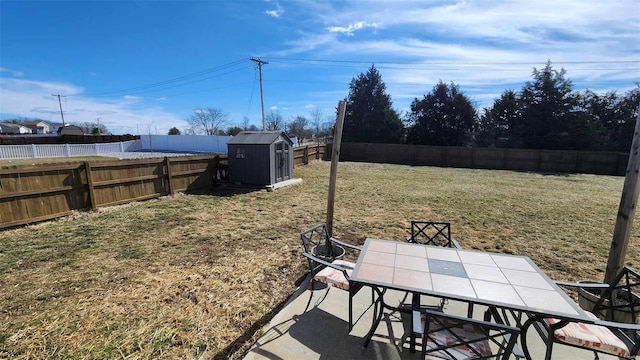 view of yard with an outbuilding, outdoor dining area, a fenced backyard, and a shed