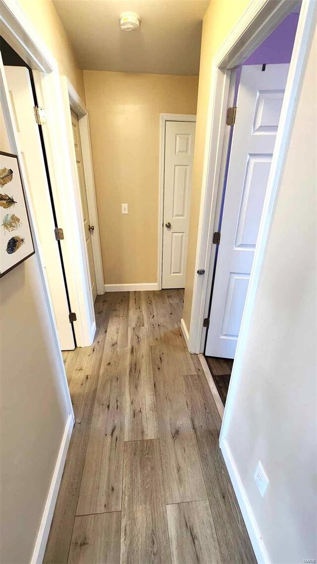 hallway with light wood-type flooring and baseboards