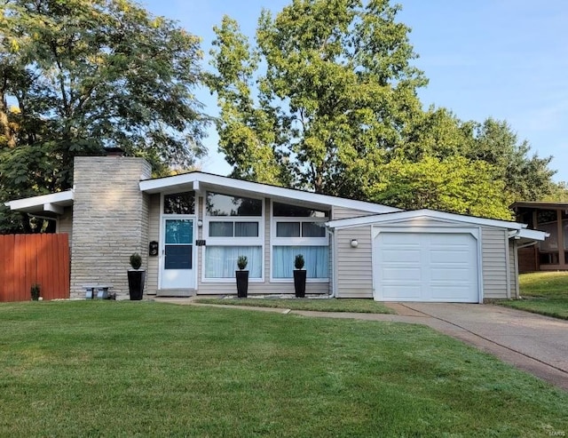 mid-century modern home featuring concrete driveway, a chimney, an attached garage, fence, and a front yard