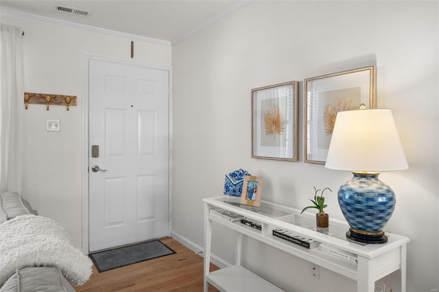 entryway featuring visible vents, wood finished floors, and ornamental molding