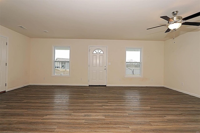 interior space with baseboards, visible vents, a ceiling fan, and dark wood finished floors