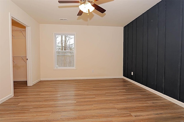 spare room with light wood-type flooring, ceiling fan, and baseboards