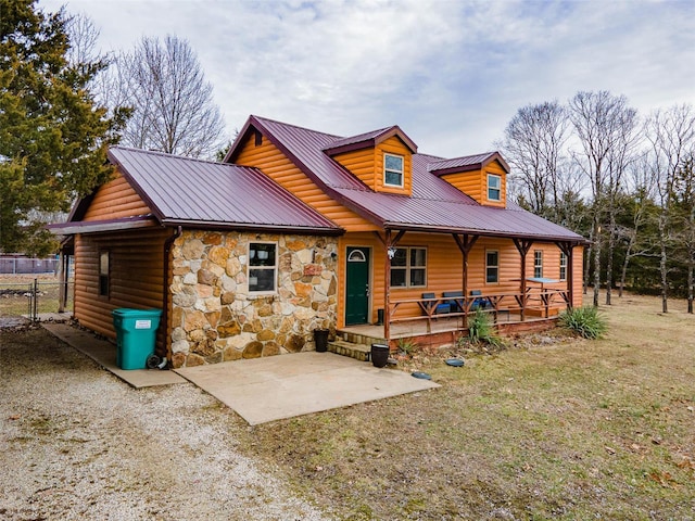 rear view of property featuring log veneer siding, stone siding, metal roof, covered porch, and a yard